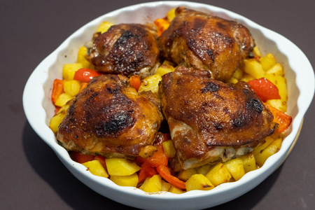 Фото к рецепту: Куриные бедра запеченные с картофелем и перцем