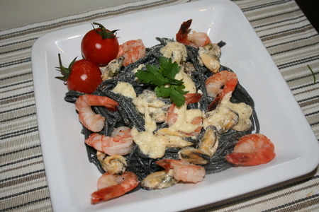 Черные спагетти с морепродуктами и сырным соусом.